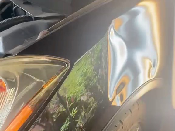 Dent on a car fender seen under a PDR light board during the repair